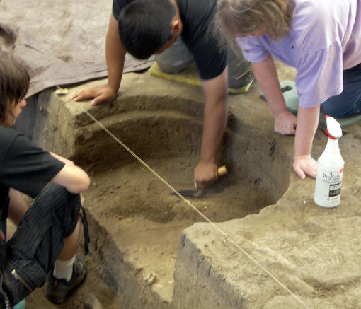 Students excavating a pit feature in side the Archeodome.