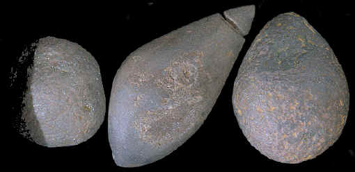 Three hematite artifacts found near a large grinding stone.